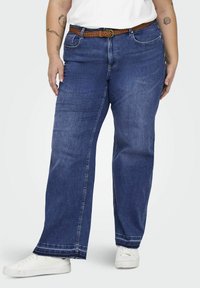 Dark blue wide-leg jeans with a braided brown belt, featuring front pockets and a stitched hem, paired with white sneakers.