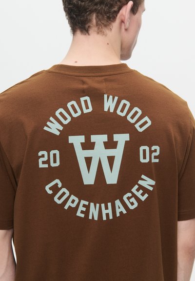 Maglietta in cotone marrone con una grande stampa in stile retro sul retro, che presenta la scritta "WOOD WOOD" e "COPENHAGEN" in lettere azzurro chiaro.