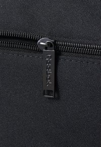 Μαύρη τσάντα φερμουάρ από ύφασμα με μεταλλικό κλιπ φερμουάρ που φέρει το ανάγλυφο όνομα της μάρκας "Reebok" σε υφή υφάσματος.