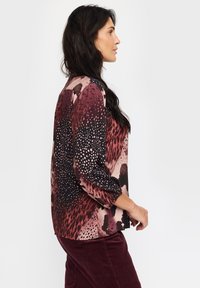 Langermet bluse med en blanding av rosa, svart og burgunder mønstre, med en avslappet passform og mykt stoff. Strukturerte detaljer gjennom hele.