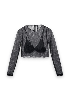 Top court en dentelle noire à manches longues, avec un voile transparent et un soutien-gorge noir uni en dessous. Tissu délicat et texturé.