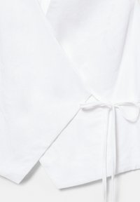 Hvid omslagsstofbeklædning med bundet sløjfe i taljen, med lange ærmer og blød tekstur.