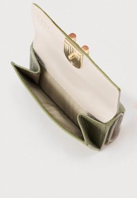 Olivzaļas krāsas ādas maks ar teksturētu ārpusi, zelta krāsas aizdari un gaiši brūnu auduma iekšpusi, kurā ir divi nodalījumi organizēšanai.