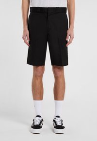 Black shorts with a straight cut, featuring a belt, smooth fabric texture, and pockets. Worn with black sneakers and white socks.