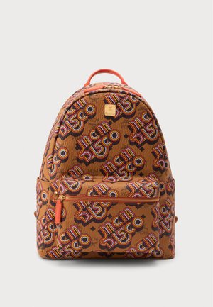 Sac à dos marron avec un motif de texte rétro coloré "MCM Disco", poche zippée frontale et poignée supérieure rouge sur fond clair uni.