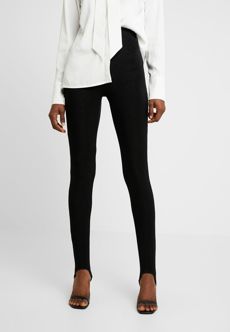 Svarta ribbade leggings med en texturerad yta, med hög midja och bärs med öppna svarta skor.