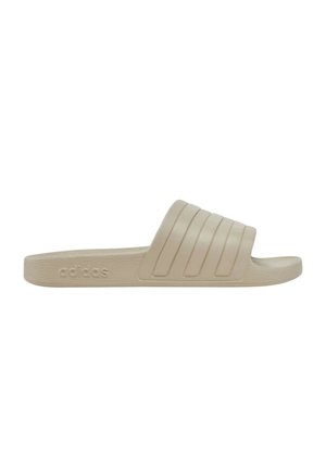 Adidas slide sandal in beige, featuring a textured sole, padded straps with horizontal grooves, and a flat design.