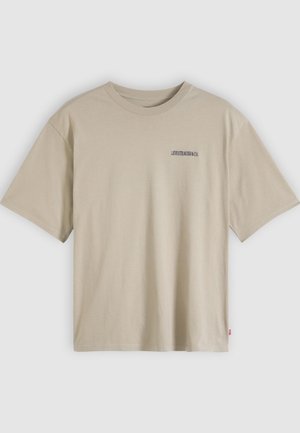 Beige bomullst-shirt med korta ärmar, rund halsringning och en liten svart logotyp på vänster bröst. Rät fåll och avslappnad passform.