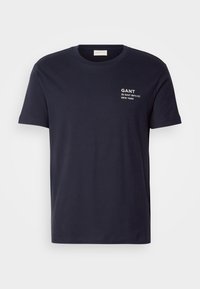 T-shirt bleu marine à manches courtes et col rond avec texte blanc "GANT 32 East 39th St. New York" sur le côté gauche de la poitrine.