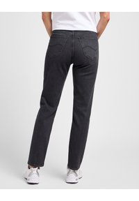 Jeans de mezclilla gris oscuro con un diseño de pierna recta, que cuentan con dos bolsillos traseros y detalles de costura sutiles. Combinados con zapatillas blancas.
