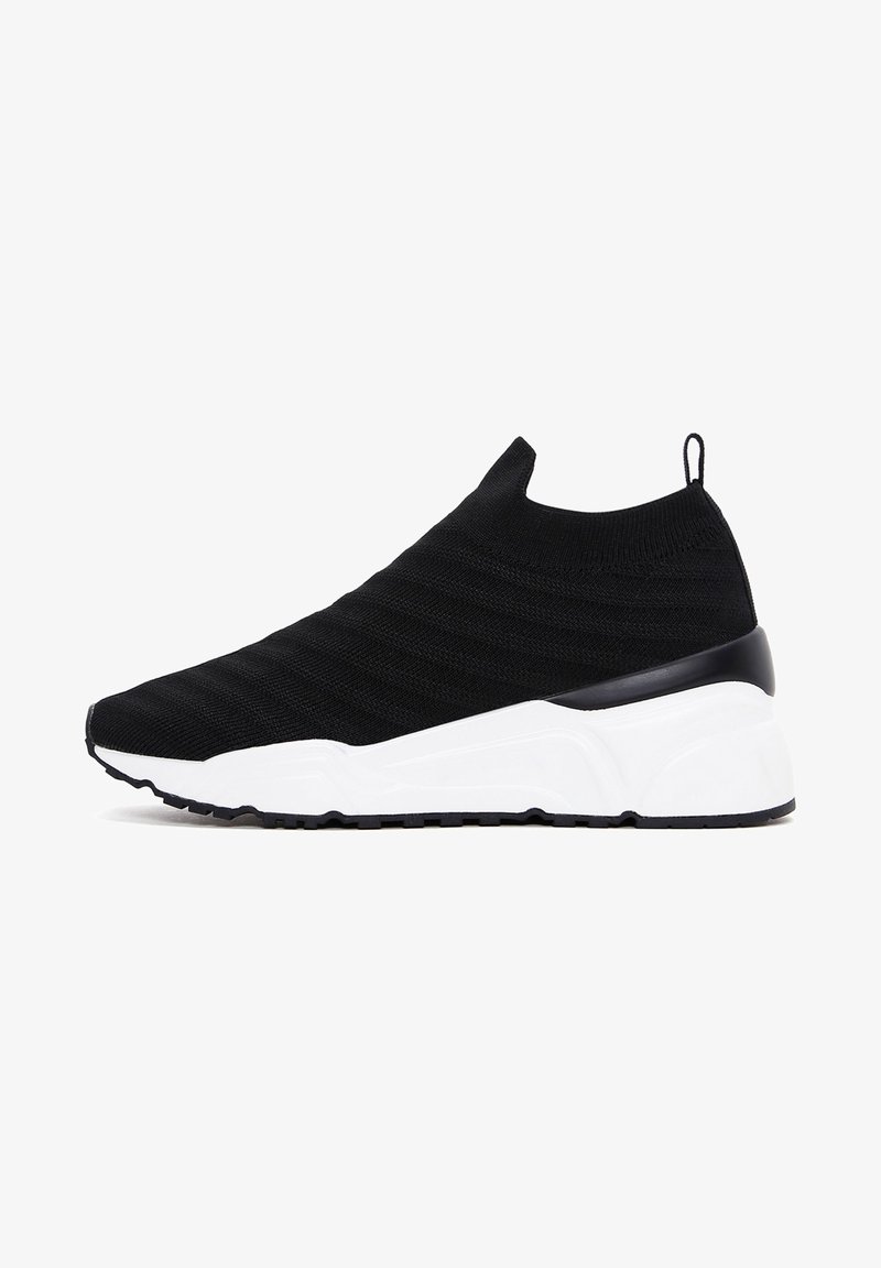 Black slip-on sneaker with knit upper, pull tab at heel, and thick white sole with black tread.