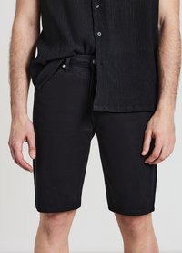 Pantaloni shorts in denim nero con taglio dritto, dotati di chiusura a bottone e cerniera, tasche laterali e una texture sottile nel tessuto.