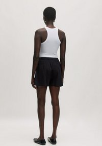 Zwarte shorts met een elastische tailleband en textuurstof, gecombineerd met een aansluitend wit tanktop. Geen opvallende patronen of accenten.