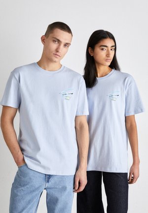 Camisetas de algodón de color azul claro con un corte holgado, que presentan un pequeño diseño bordado multicolor en el pecho. Tienen mangas cortas y cuello redondo.