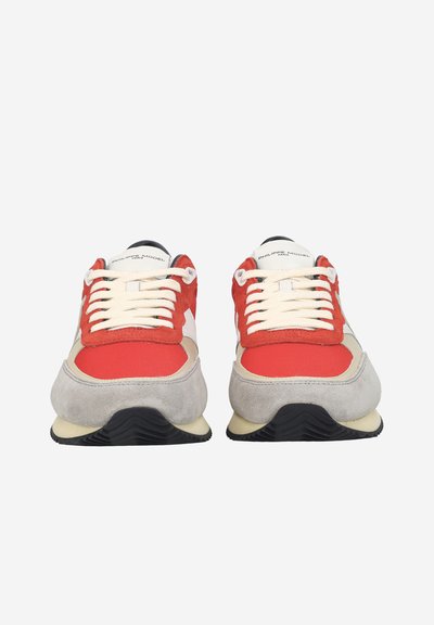 Paire de baskets rouges, beiges et grises avec des lacets blancs, vues de face sur un fond blanc.