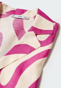 Blouse à col en tissu léger présentant des motifs tourbillonnants abstraits audacieux en rose et crème, avec une finition texturée et une étiquette cousue.