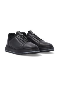 Schwarze Lederschuhe mit glatter Textur und abgerundeter Form. Merkmale sind Schnürsenkel, ein kontrastierender Akzent auf der Zunge und eine dicke Sohle.
