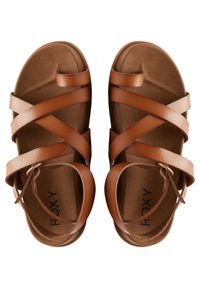 Sandales en cuir marron avec de larges sangles croisées, une semelle plate et une bride au niveau de la cheville. Le pied est doté d'une finition texturée. La marque est visible.