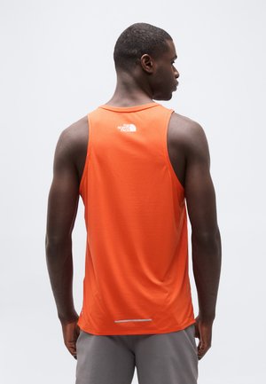 Mann iført oransje ermeløs treningsgenser med "The North Face"-logo på baksiden, sett bakfra mot en ensfarget lys bakgrunn.