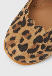 Slip-on παπούτσι από σουέτ με λεοπάρ σχέδιο, διαθέτει κυματιστή άκρη και λείο εσωτερικό επένδυμα. Μαλακή υφή με στρογγυλεμένη μύτη και επίπεδη σόλα.