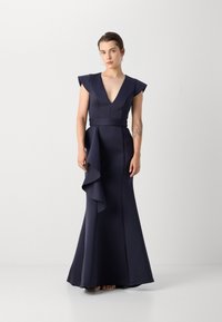 Robe de soirée bleu marine avec des manches courtes, décolleté en V, corsage ajusté et un détail en volants fluide au niveau des hanches, confectionnée dans un tissu lisse et extensible.