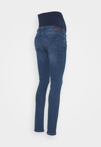 Gravidjeans med midjeband i mörkblå, elastisk över magen och en smal passform. Tillverkade av denim med en medel tvätt och standard sömnad.