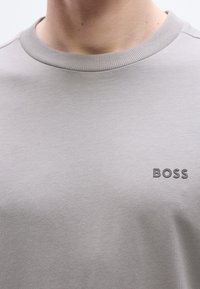 Γκρι βαμβακερό t-shirt με ριμπ ύφανση στο λαιμό και διακριτικό ανάγλυφο λογότυπο 'BOSS' στο στ ήθος. Ομαλή υφή, εφαρμοστή γραμμή.
