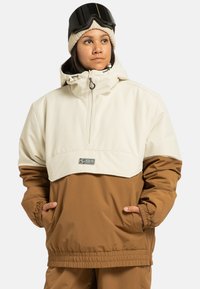 Beżowa i brązowa narciarska kurtka z kapturem, z pół-zamkiem z przodu, elastycznymi mankietami i naszywką z logo. Gładka faktura z luźnym krojem.