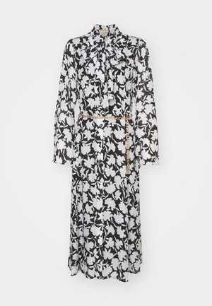 Blumenkleid in Schwarz und Weiß, mit langen Ärmeln, einem Schleifenkragen, durchgehender Knopfleiste und einem goldenen Kettengürtel in der Taille.