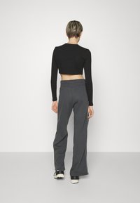 Svart kortärmad topp med långa ärmar, parat med grå vida byxor med sidoremsor och en mjuk, texturerad väv.