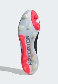 Semelle de crampons de football noire avec une semelle extérieure transparente et des pointes roses et vert néon. "PREDATOR" est affiché en gris.
