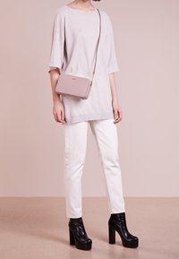 Ljusgrå oversized t-shirt, vita jeans och svarta plattformstövletter. Accenterad med en liten rosa crossover-väska med guldkedja.