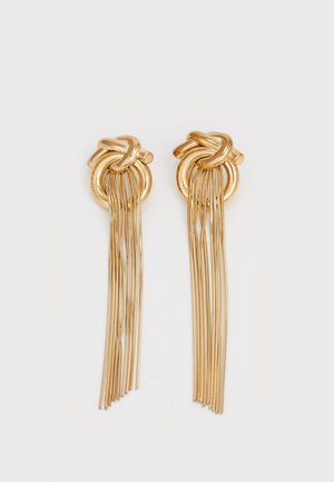 Gold-tone hoop earrings featuring a knot design with long metal fringe. Smooth texture with a shiny finish, creating a bold visual effect.
