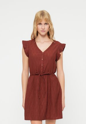 Κόκκινο υφασμάτινο φόρεμα με κοντά φτερωτά μανίκια, λαιμόκοψη V, κουμπιά στο μπροστινό μέρος και λεπτομέρεια δεσίματος στη μέση. Το ύφασμα έχει κυματιστό σχέδιο.