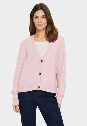 Pink knitted cardigan with a v-neck, featuring wooden buttons and ribbed cuffs. Paired with a light top and dark denim jeans.