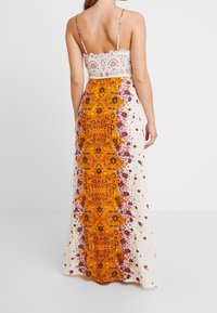 Maxi šaty s krajkovým tělem, nastavitelnými popruhy a květinovými vzory v oranžové a fialové barvě na bílém pozadí, s volným střihem.