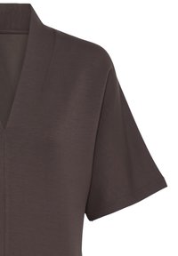 Chemise marron foncé à manches courtes avec un col en V et une texture de tissu propre et lisse montrée sur fond blanc.