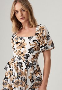 Floral dress with a square neckline, puffed sleeves, and a tie waist. Features black and gold flowers on a white background. Lightweight fabric.