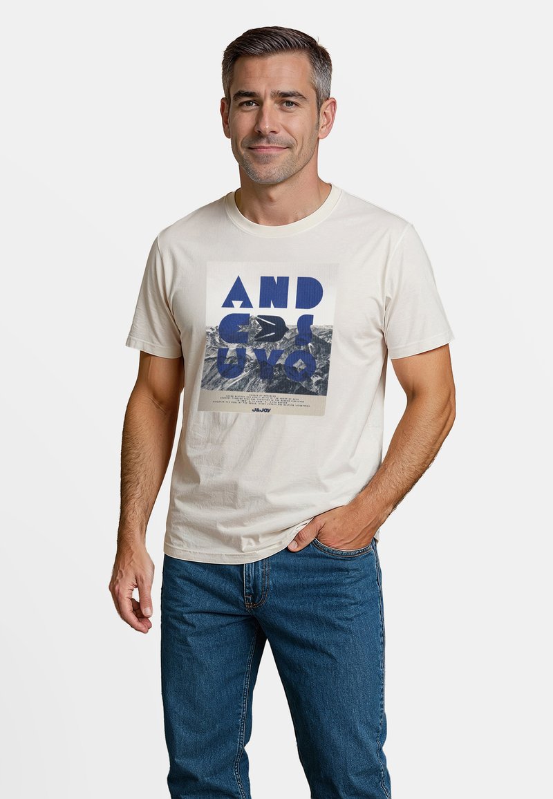 Lichtbeige katoenen t-shirt met een grafische print van blauwe tekst en een zwart ontwerp op een grijze bergachtergrond. Korte mouwen, klassieke pasvorm.