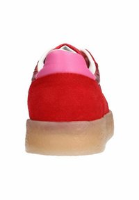Rode suède sneaker met een roze en witte kraag, voorzien van een doorzichtige rubberen zool. Het ontwerp is laag bij de grond met een ronde vorm.