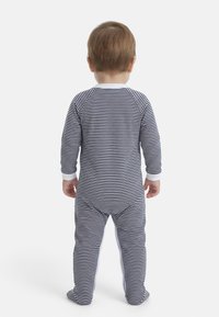 Νήπιο όρθιο, γυρισμένο με την πλάτη, φοράει πυτζάμες με οριζόντιες ρίγες σε ναυτικό μπλε και λευκό, με καλυμμένα τα πόδια.