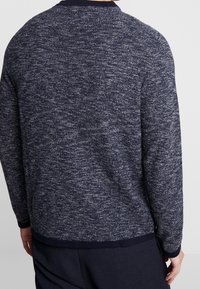 Maglione lavorato a maglia blu navy con finitura testurizzata, scollo a girocollo e polsini e orlo rigati, impreziosito da un delicato motivo melangiato.