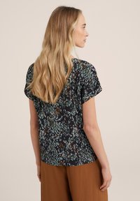 Blusa a maniche corte con una base nera e un motivo geometrico multicolore. Tessuto morbido, vestibilità rilassata e orlo arrotondato.