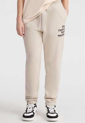 Beige sweatpants gjorda av mjukt tyg, med en elastisk midjeband och ärmmuddar. Tryckt text på sidan lyder: "The Future Surf Society."