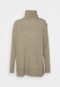 Beige kabelstickad tubtröja med långa ärmar och en rad av fem bruna knappar längs vänster axel och krage.