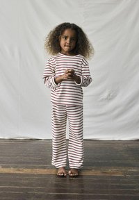 Pigiama a righe in crema e rosso, composto da una maglietta a maniche lunghe e pantaloni larghi, realizzati in tessuto morbido, con scollatura aperta.