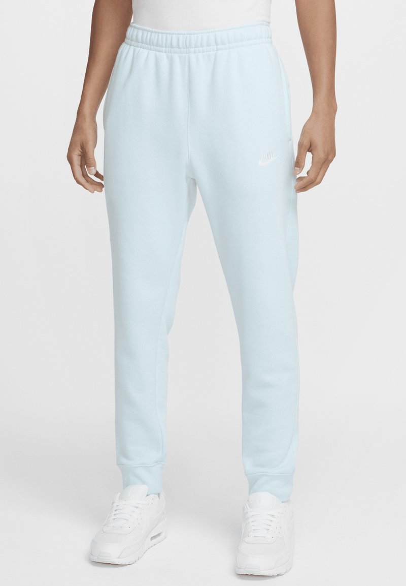 Pantalones de chándal azul claro hechos de una tela suave, con una cintura y puños elásticos, y un pequeño logo blanco de Nike en el muslo izquierdo.