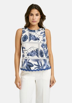 Floral-patterned sleeveless top in cream and navy, round neckline, scalloped hem, featuring botanical designs and a loose fit.