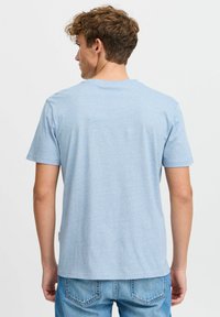 Light blue short-sleeve t-shirt made of soft fabric, featuring a round neckline and a slightly textured surface, worn with blue jeans.