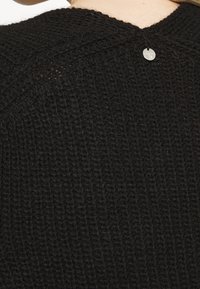 Schwarzer gestrickter Pullover mit strukturiertem Muster, V-Ausschnitt und einem dekorativen Metallknopf auf der Rückseite. Weiches, dickes Material.